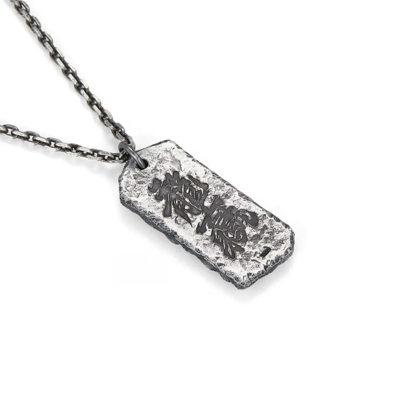 Back view of the Abundance necklace pendant, showing engraved black Chinese calligraphy on a textured surface