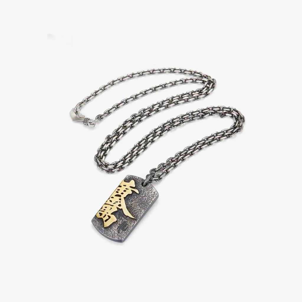 Flat lay of the Fortune necklace with a rugged silver chain and rectangular amulet pendant