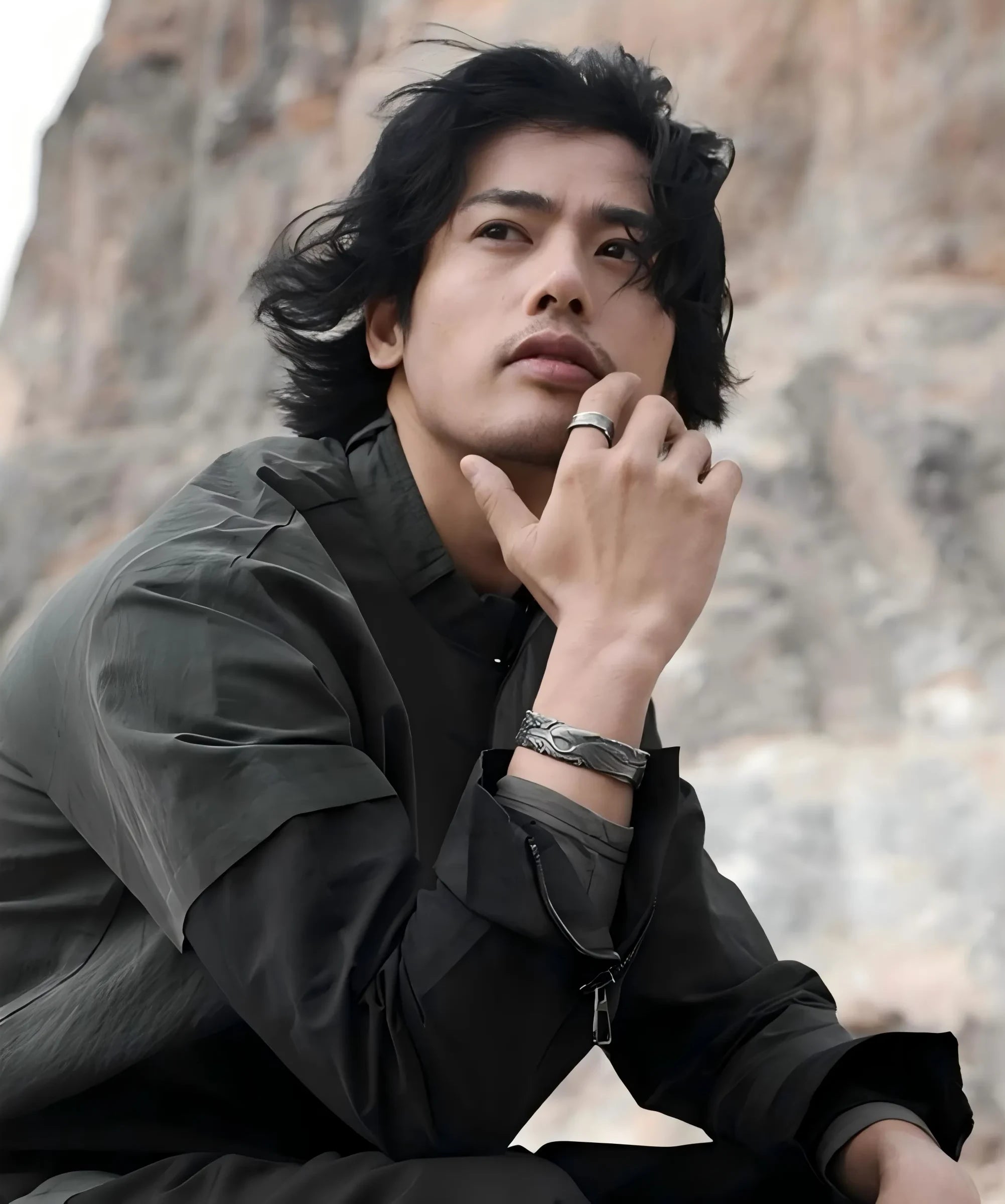 Profile shot of the model touching his face, emphasizing the bangle's rugged texture which complements a masculine, artistic look