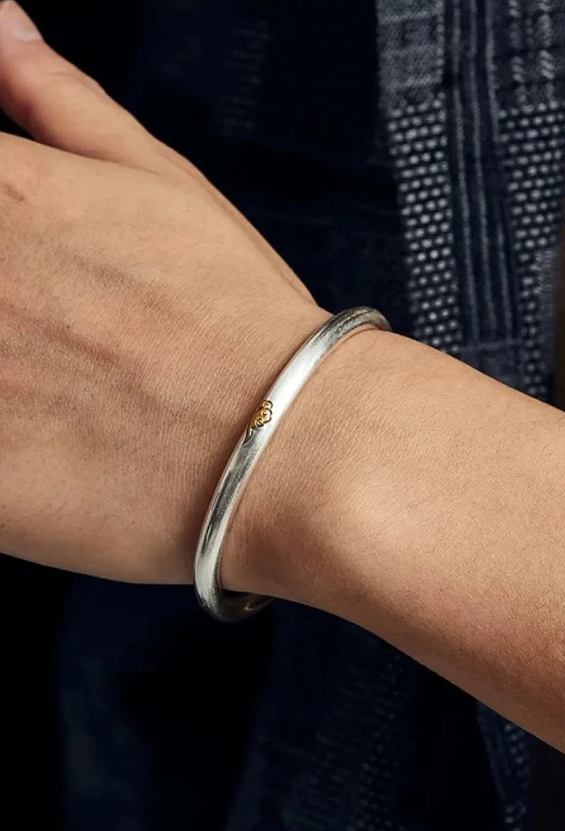 Model styling the bangle with a textured shirt, demonstrating how the piece adds a touch of Zen elegance to a modern outfit