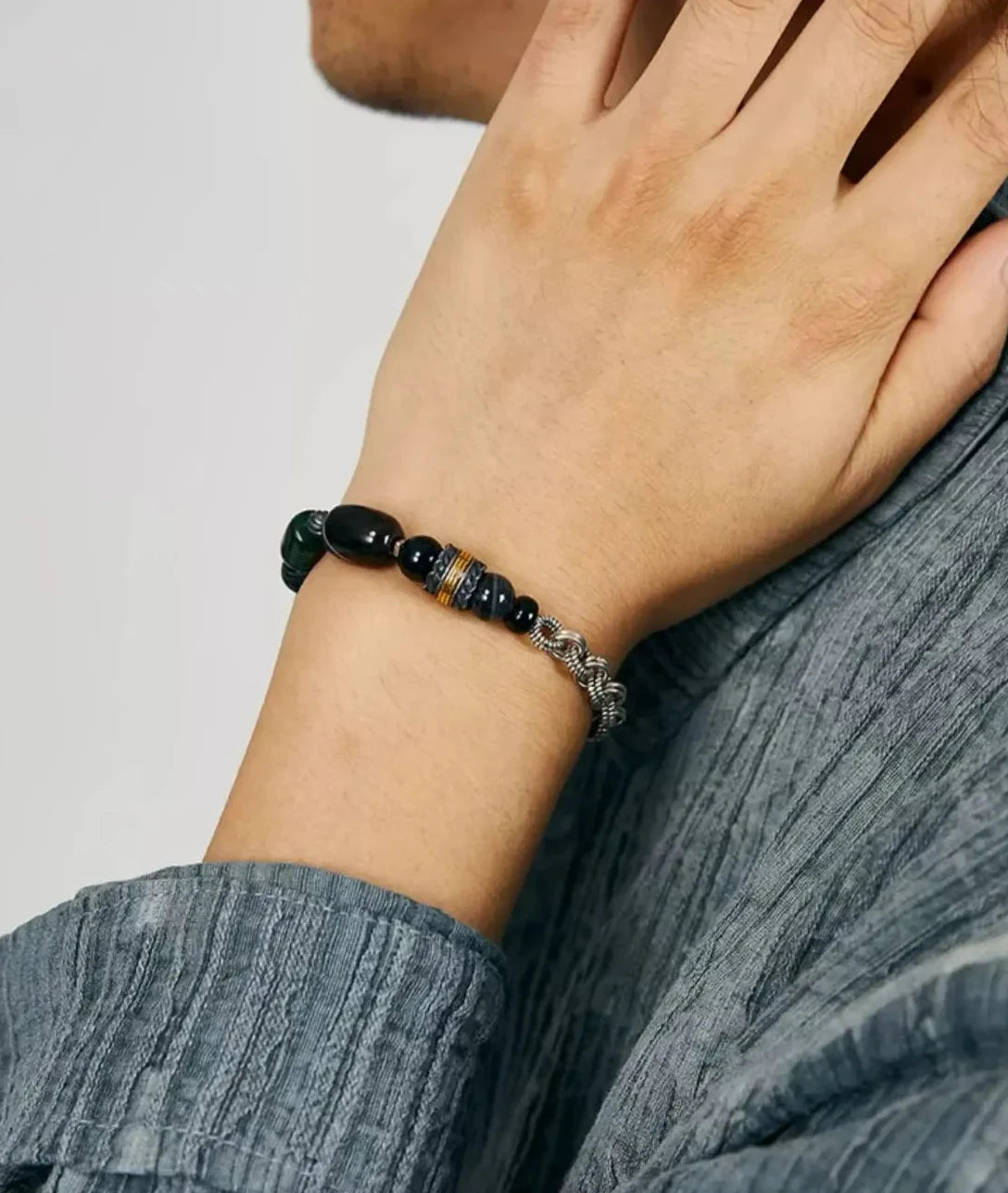 Close-up on the wrist featuring the prominent black banded agate bead, symbolizing focus and protection