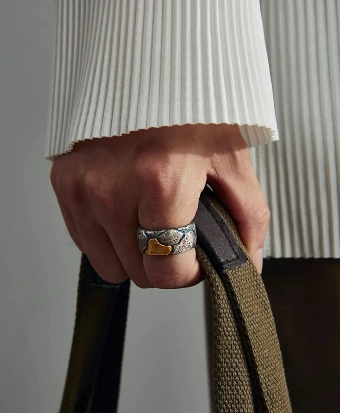 Model wearing the Bedrock Ring while holding a bag, showcasing a bold men's streetwear fashion accessory