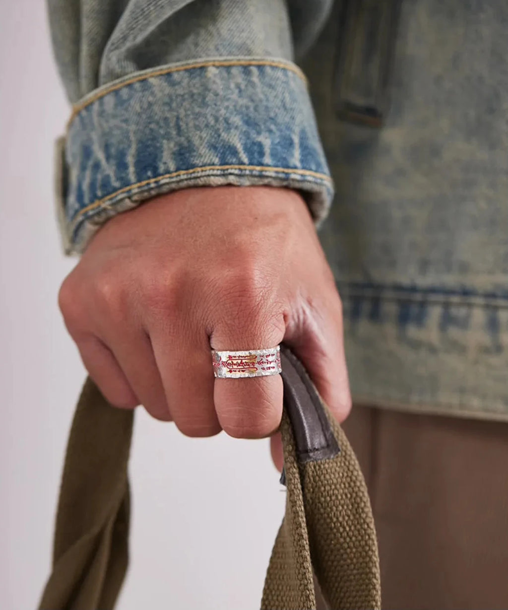 Model clenching a fist to showcase the bold design and red cinnabar details of the handcrafted silver ring