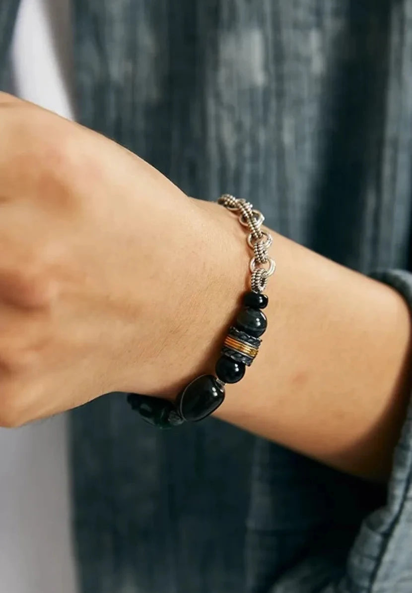 A candid shot showing the bracelet worn with a grey textured shirt, highlighting its versatility for casual and industrial styles