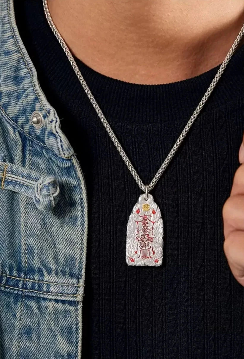 Front view of the Taoist amulet necklace resting on the model's black shirt, showing the vermilion script clearly