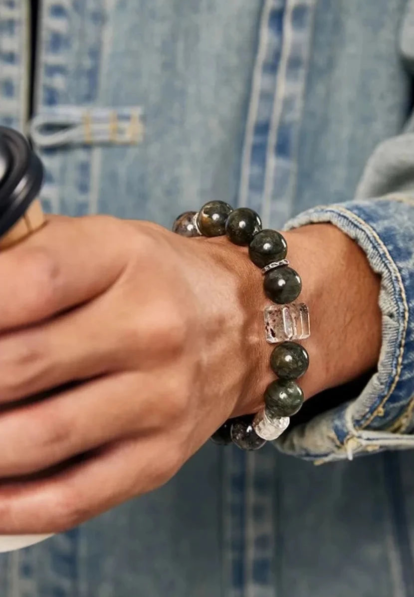 Close-up of the bracelet on a wrist holding a coffee cup, showing how the dark green tones match everyday life