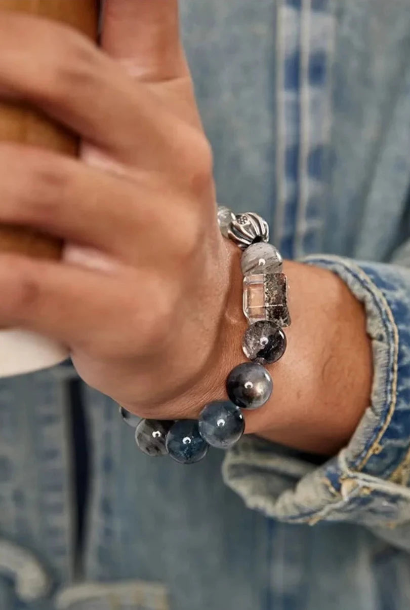 Close-up of the bracelet on a wrist holding a coffee cup, highlighting the translucency of the crystals in natural light