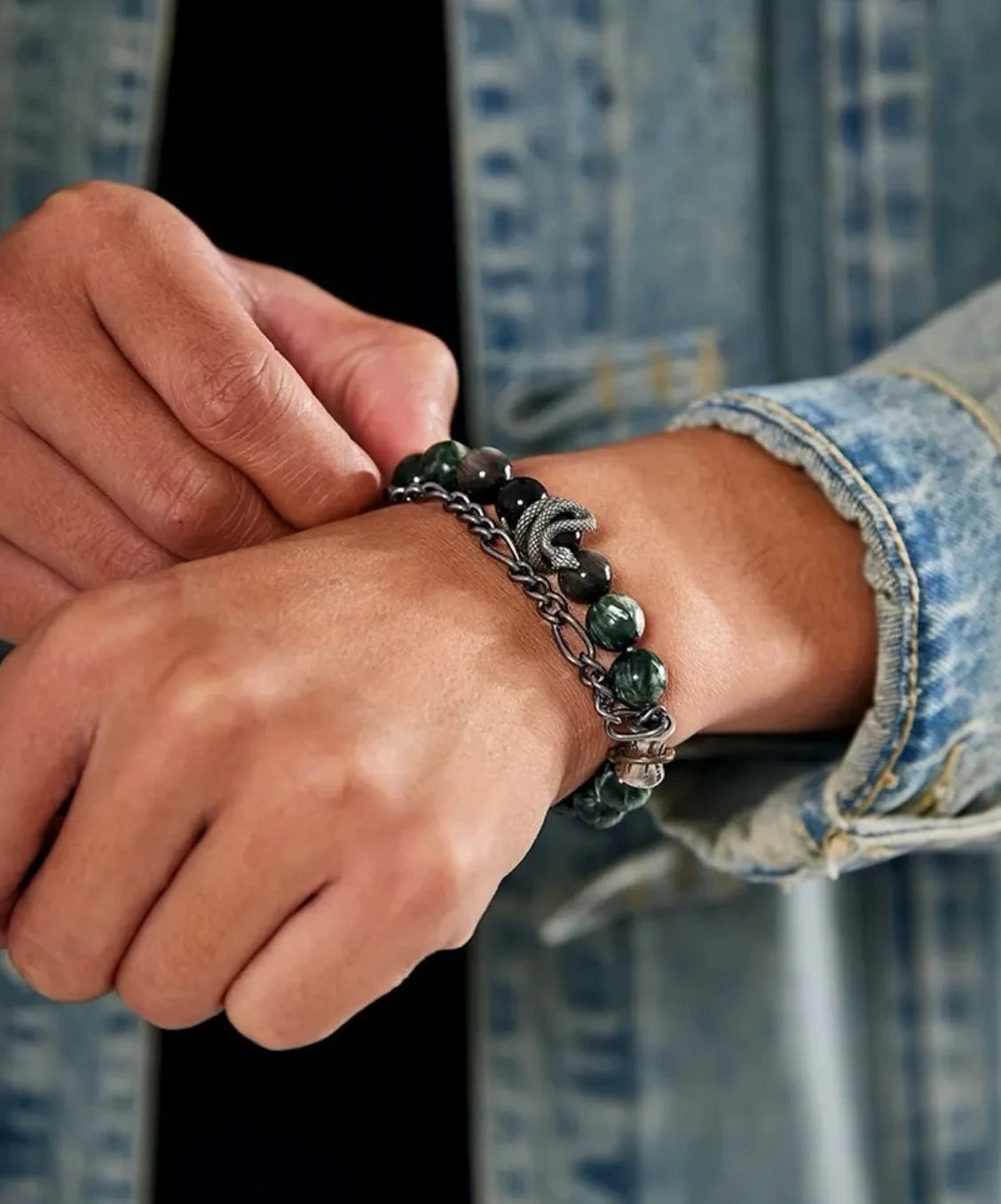 Lifestyle shot of a man in a distressed denim jacket adjusting the Python Bracelet, showcasing its edgy, masculine vibe