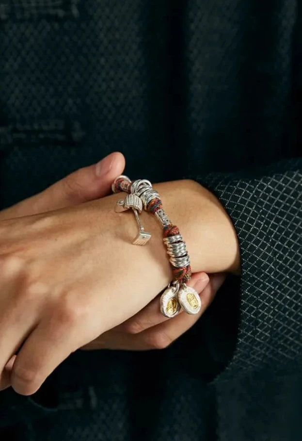 Lifestyle shot of a man wearing a textured dark jacket, showcasing the colorful 'Dream Digger' bracelet on his wrist