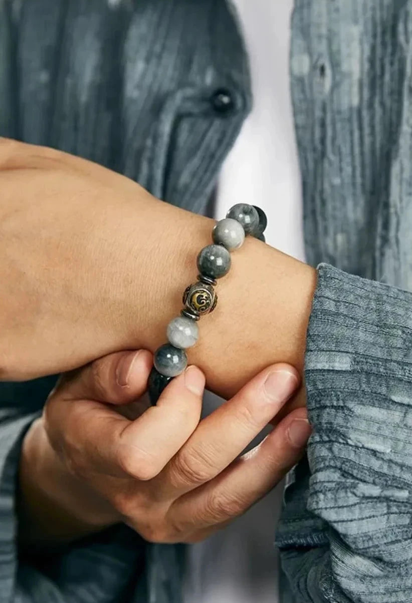 Close-up on the wrist capturing the "cat's eye" light reflection of the grey beads under natural light