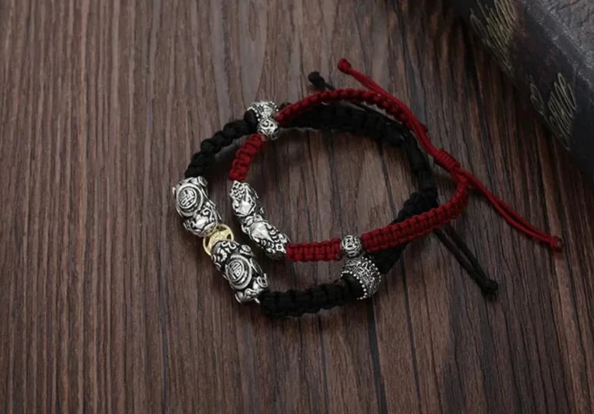 Artistic shot of the two bracelets overlapping, symbolizing the balance of Yin (Red) and Yang (Black) energies and the bond between partners