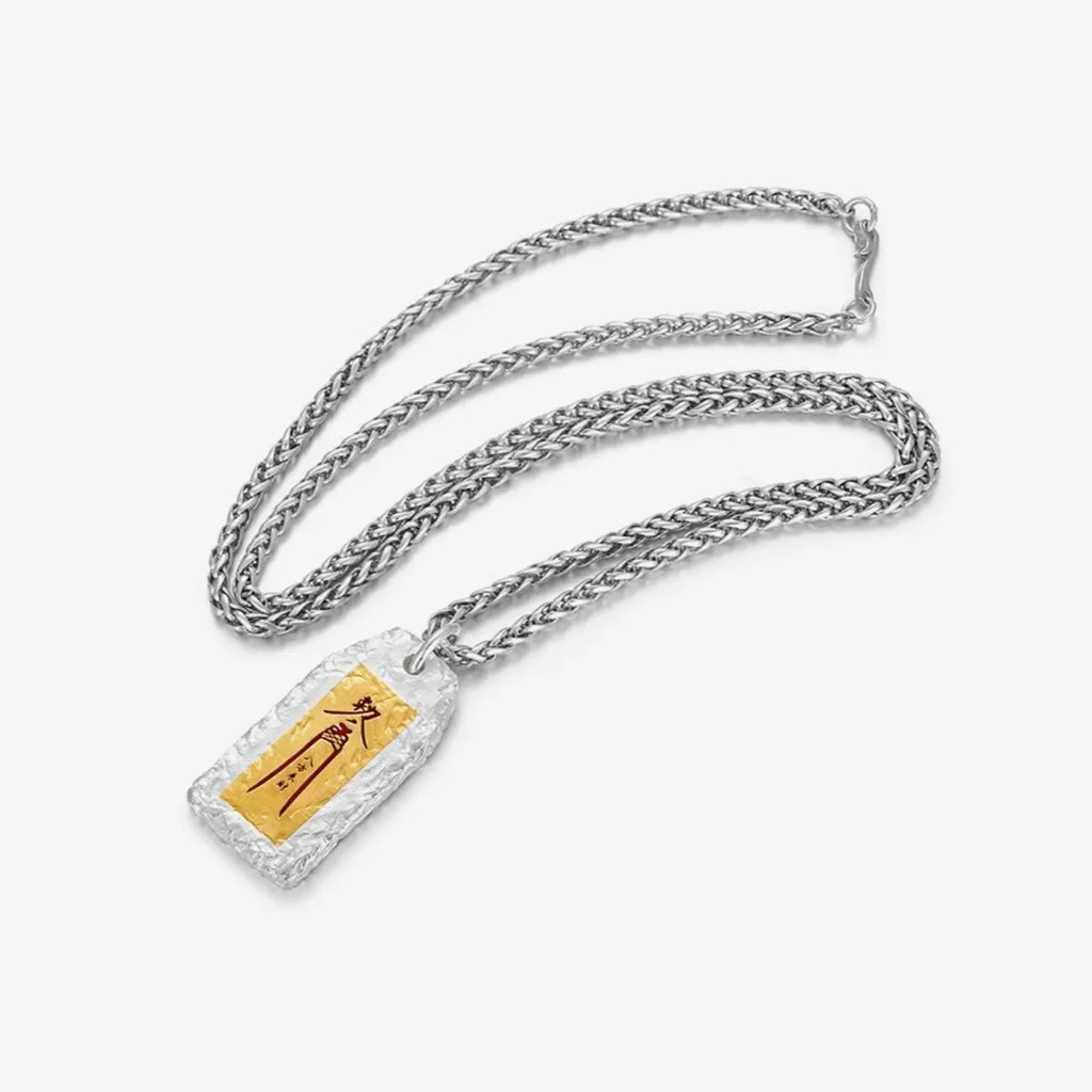 Flat lay display of the Feng Shui good luck necklace with a silver wheat chain on a white background
