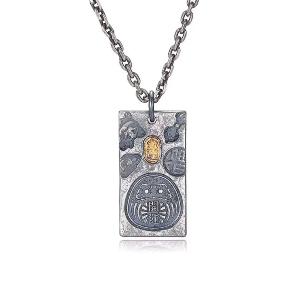 Front view of the Fortune Key necklace featuring a silver Daruma amulet with gold and bronze accents