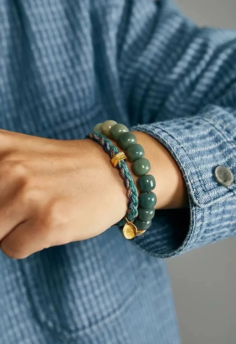 A serene shot of a man in a contemplative pose, highlighting the bracelet as a symbol of wisdom, peace, and mindfulness