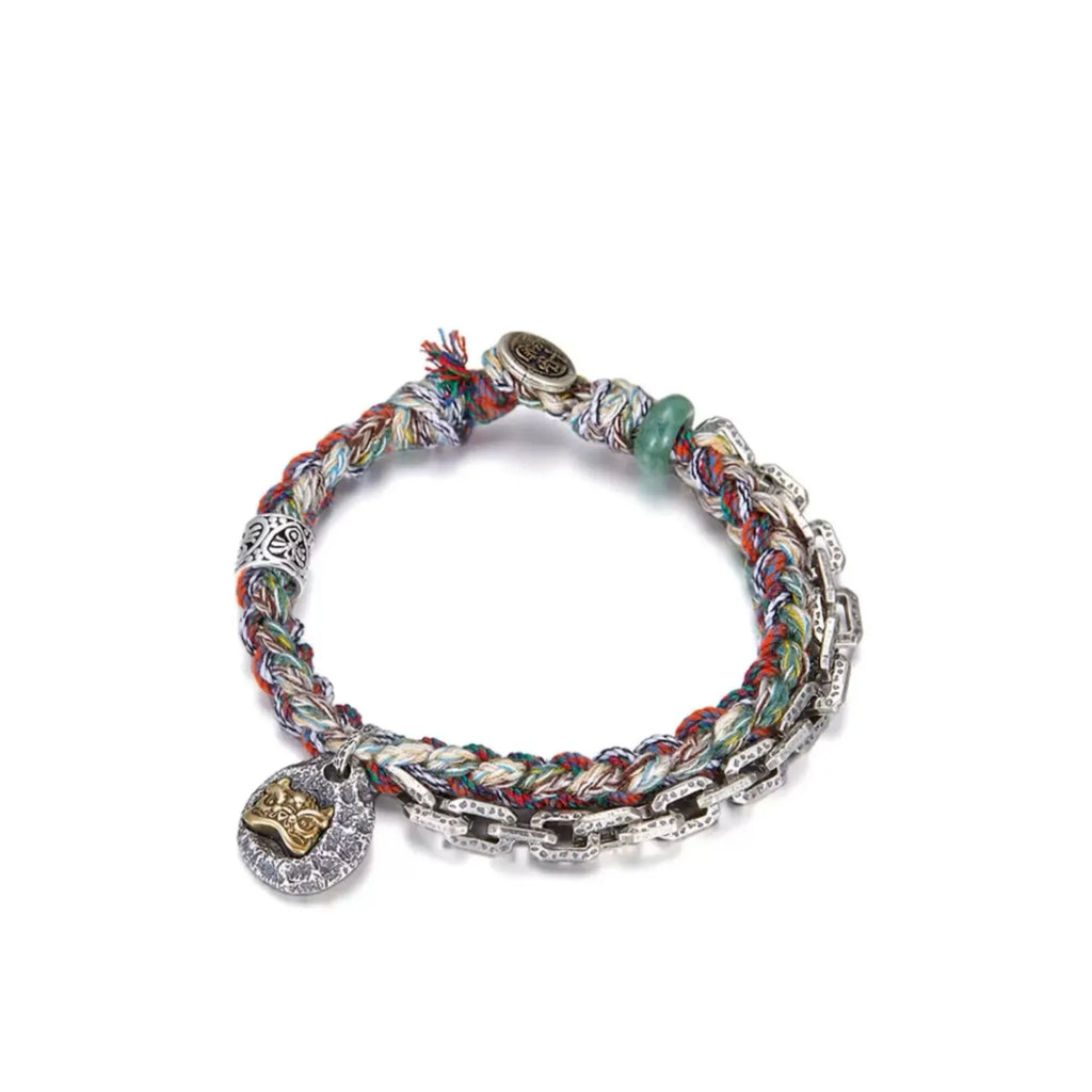 Front view of the Awakening Lion bracelet, featuring a golden guardian lion charm set on a hammered silver tag, intertwined with a colorful woven cord