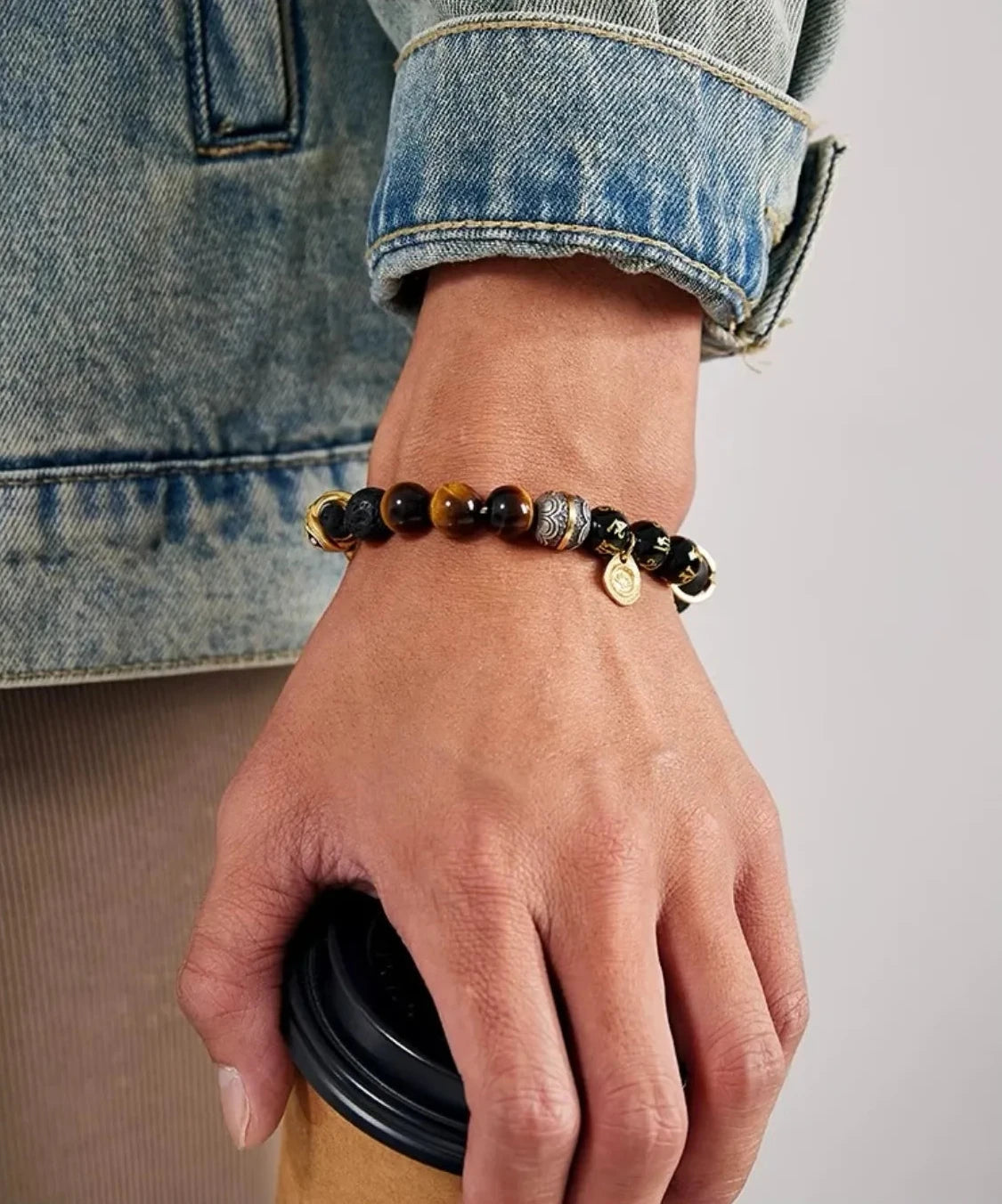 Lifestyle shot of a man holding a coffee cup, wearing the Destiny Bracelet as a symbol of ambition and business success