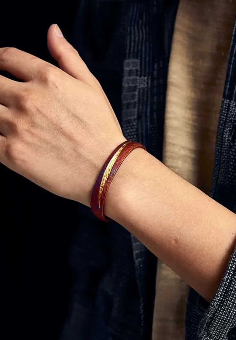 Clear shot of the bangle on the wrist, showing how the gold line catches the light and the red patina complements skin tones