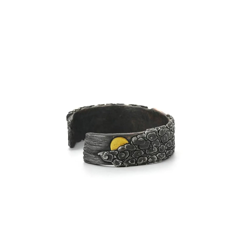 Side profile showing the rugged, rock-like texture of the bangle edges and the bronze undertones of the crane design