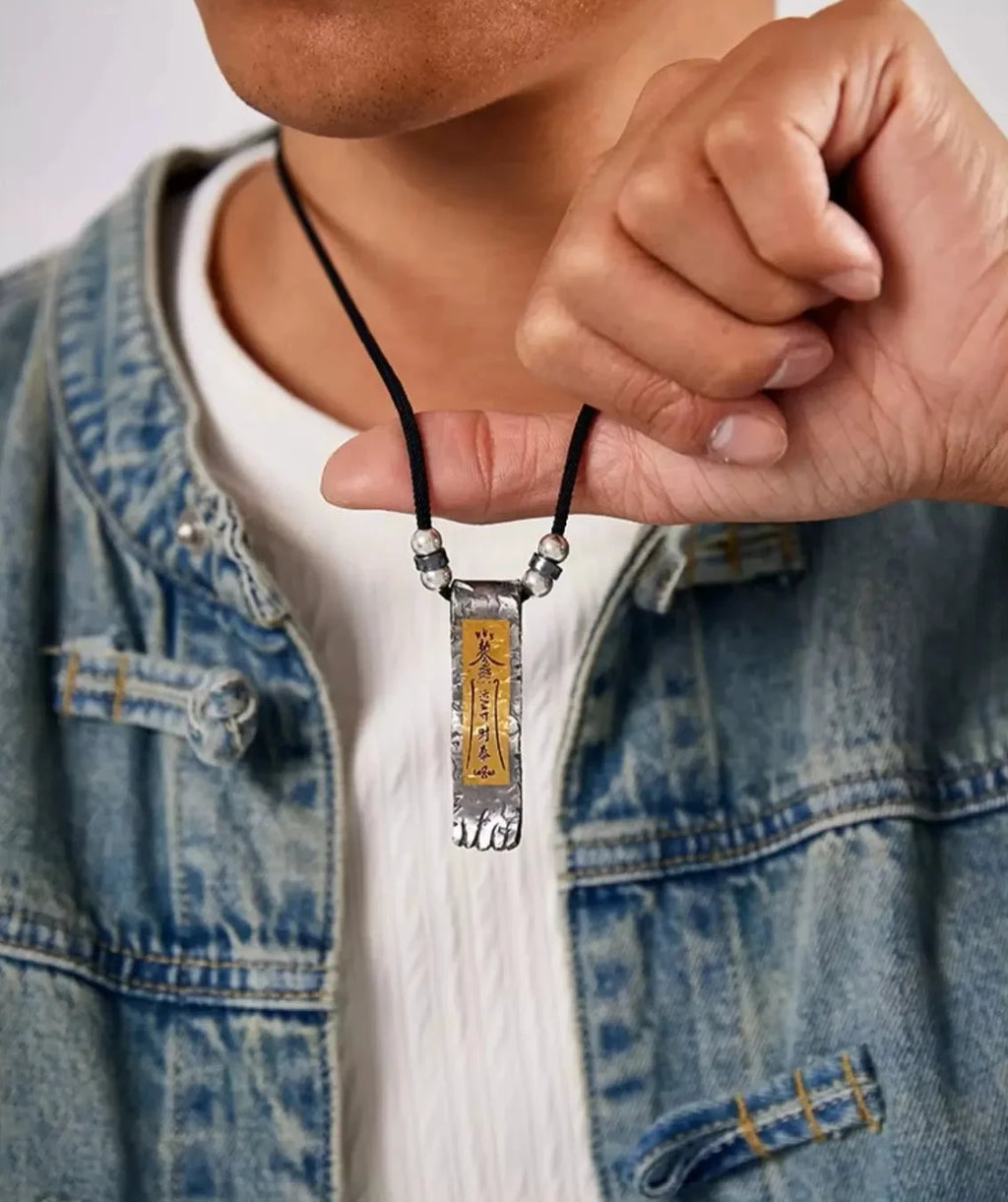 Man holding the gold and silver amulet pendant to show its scale
