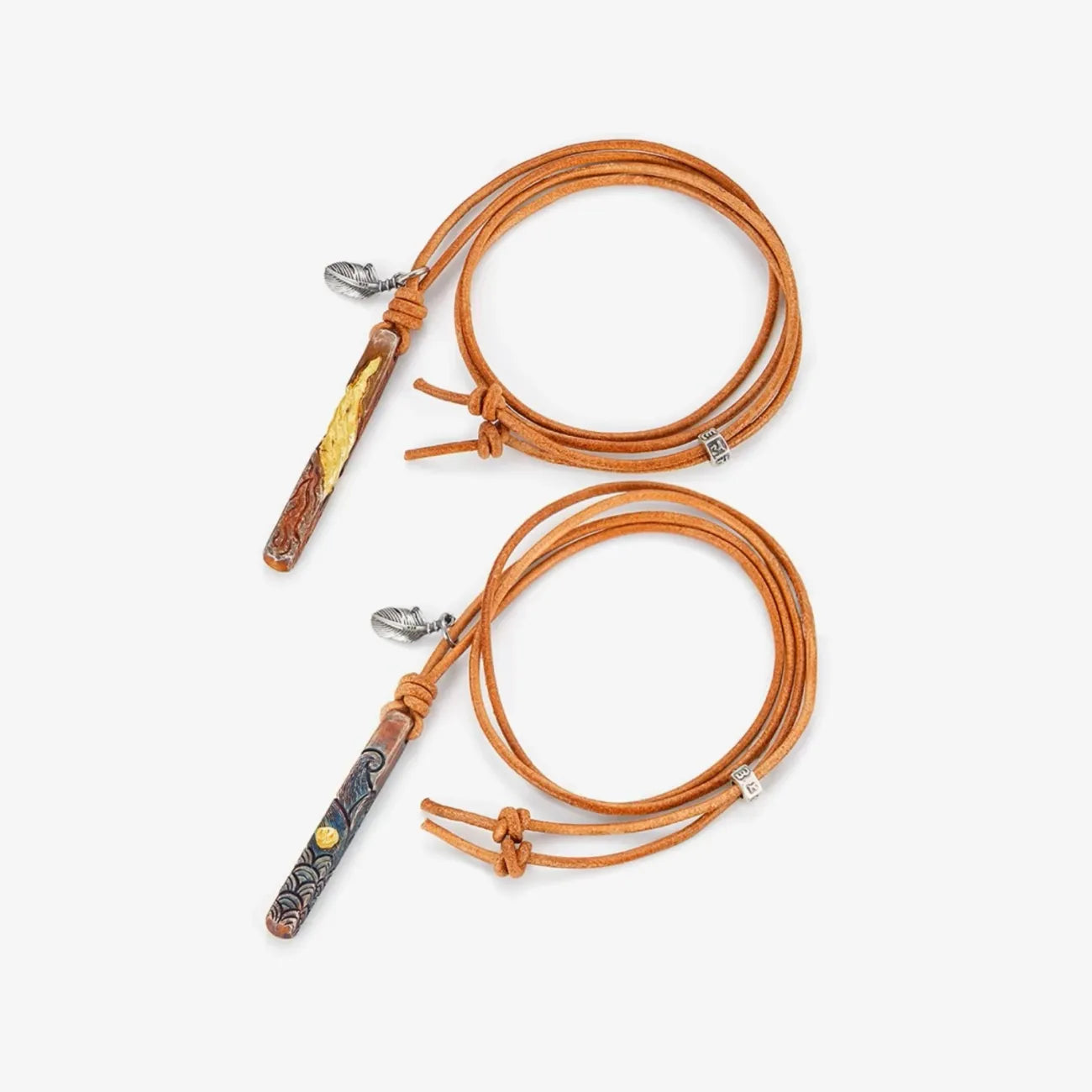 Flat lay of the couple's necklaces with coiled leather cords and elemental totem pendants