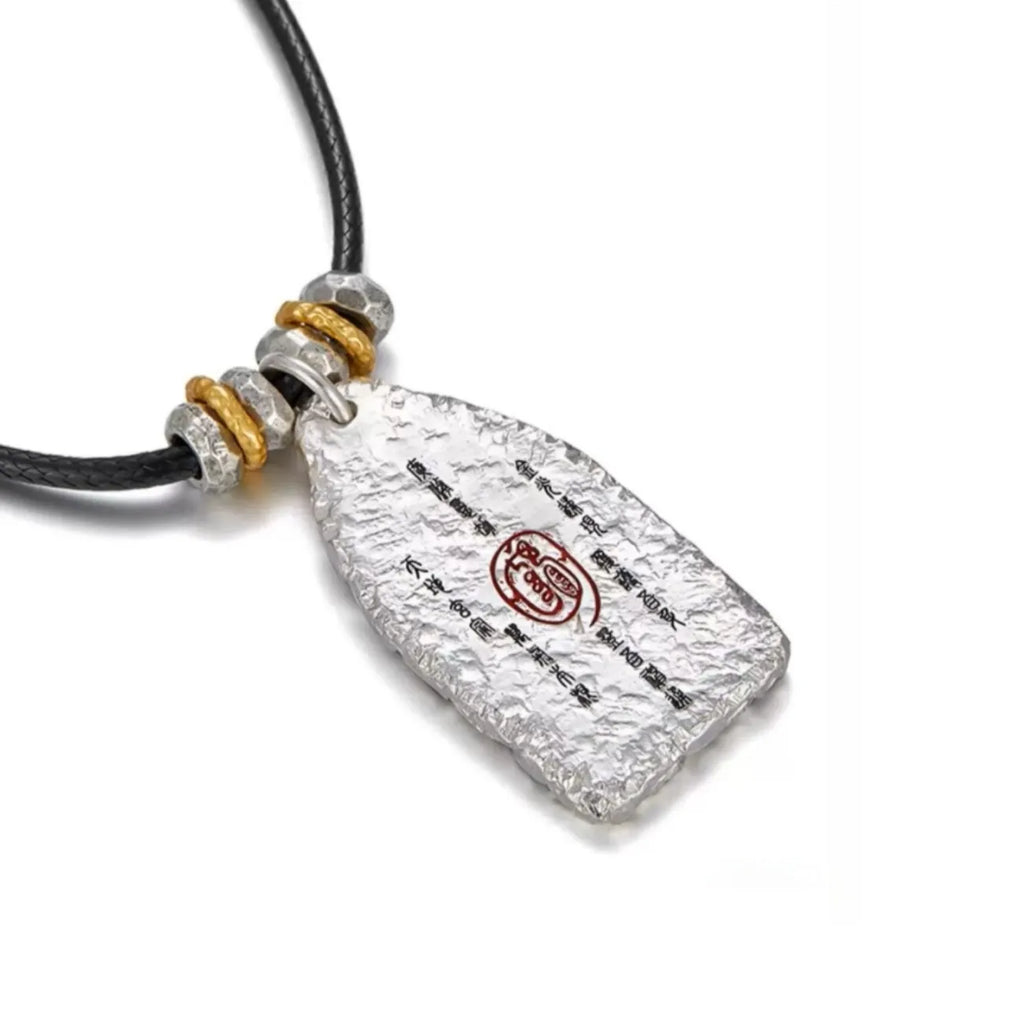 Side view of the Taoist amulet on a leather cord, highlighting the golden and silver spacer beads