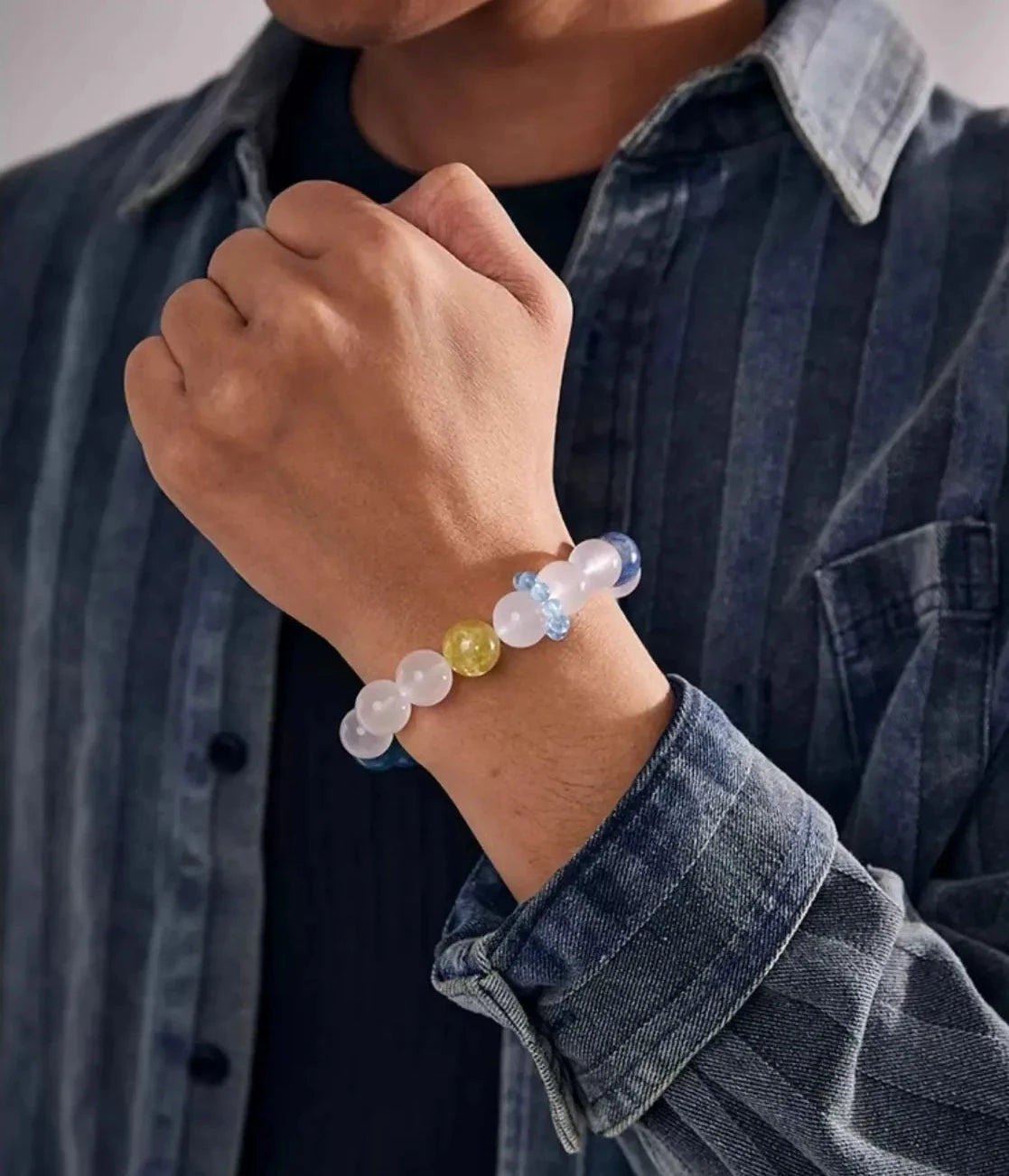 Lifestyle shot of a man in a striped denim shirt, wearing the Kyanite bracelet that perfectly matches his intellectual style