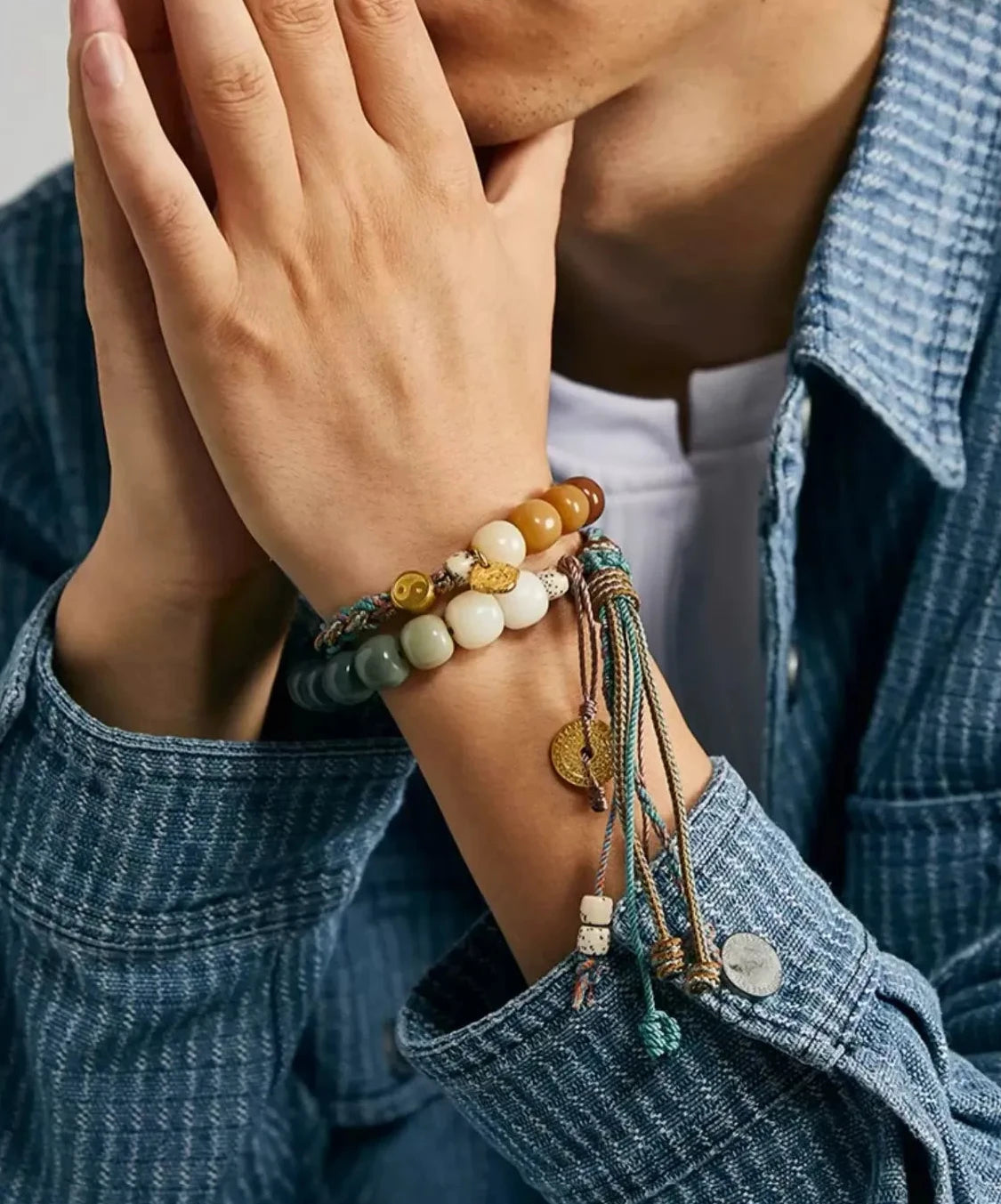 Lifestyle shot of a man holding a bag, wearing the gradient beaded bracelet that perfectly matches his blue denim shirt