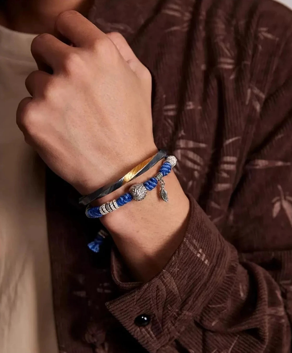 Close-up on the wrist focusing on the dangling silver leaf/feather charm, symbolizing freedom and nature