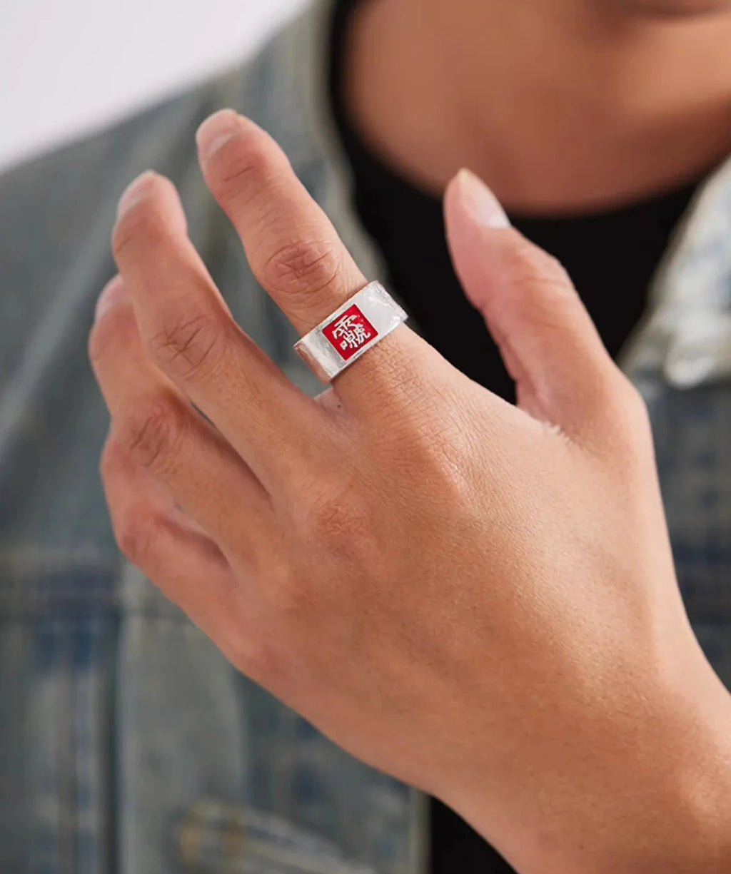 Lifestyle shot of a man wearing the red square silver ring with a denim jacket, holding a canvas bag strap