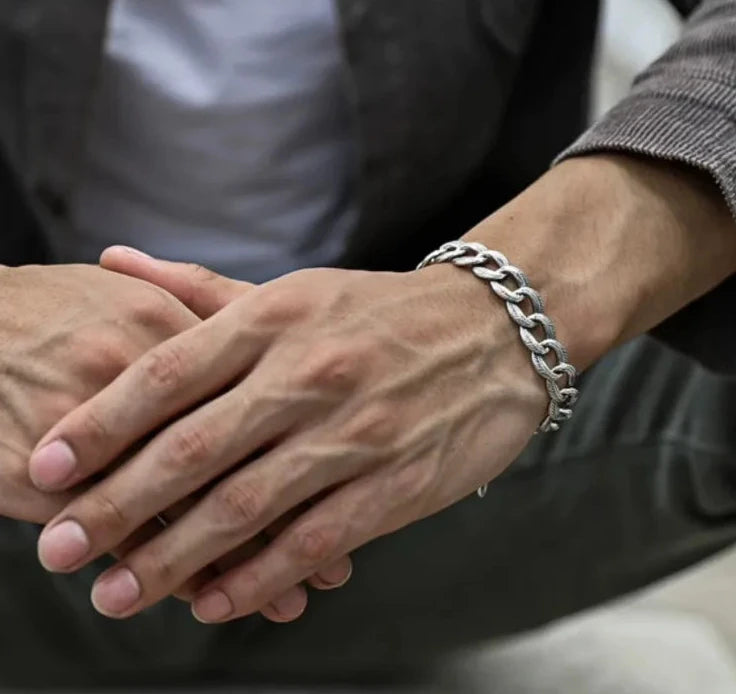 Close-up of clasped hands, emphasizing the intricate feather details and how the bracelet complements vascular arms