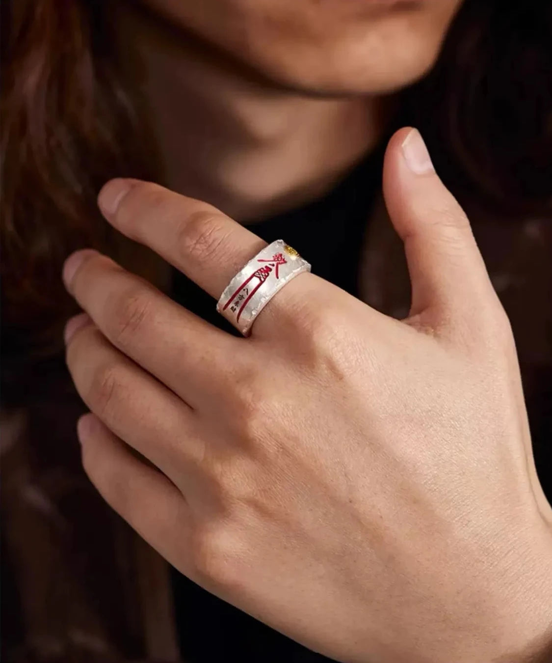 Lifestyle shot of a man wearing the silver and gold Taoism ring on the middle finger while holding a coffee cup