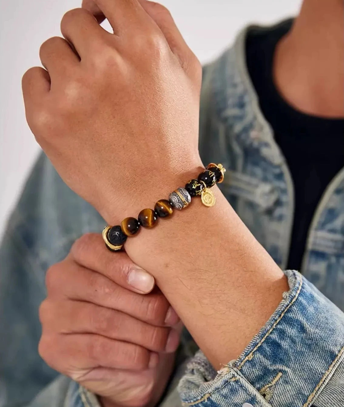 A man adjusting his bracelet, demonstrating the versatile style that fits both casual streetwear and smart casual outfits