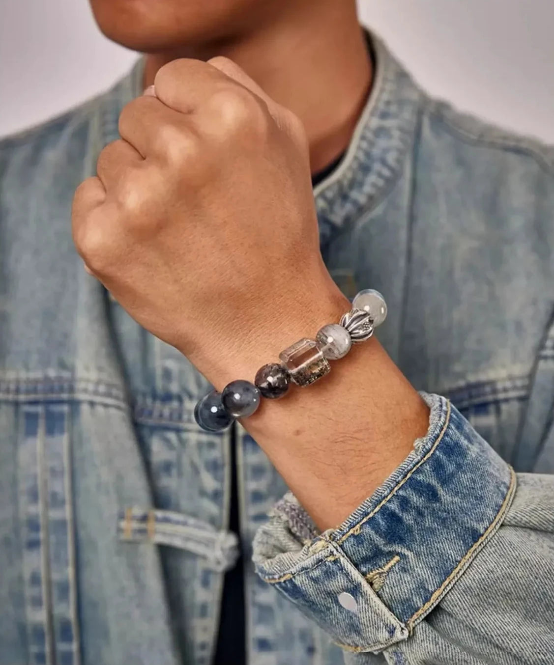 Lifestyle shot of a man wearing a denim jacket, showcasing the blue gemstone bracelet that perfectly matches the casual outfit