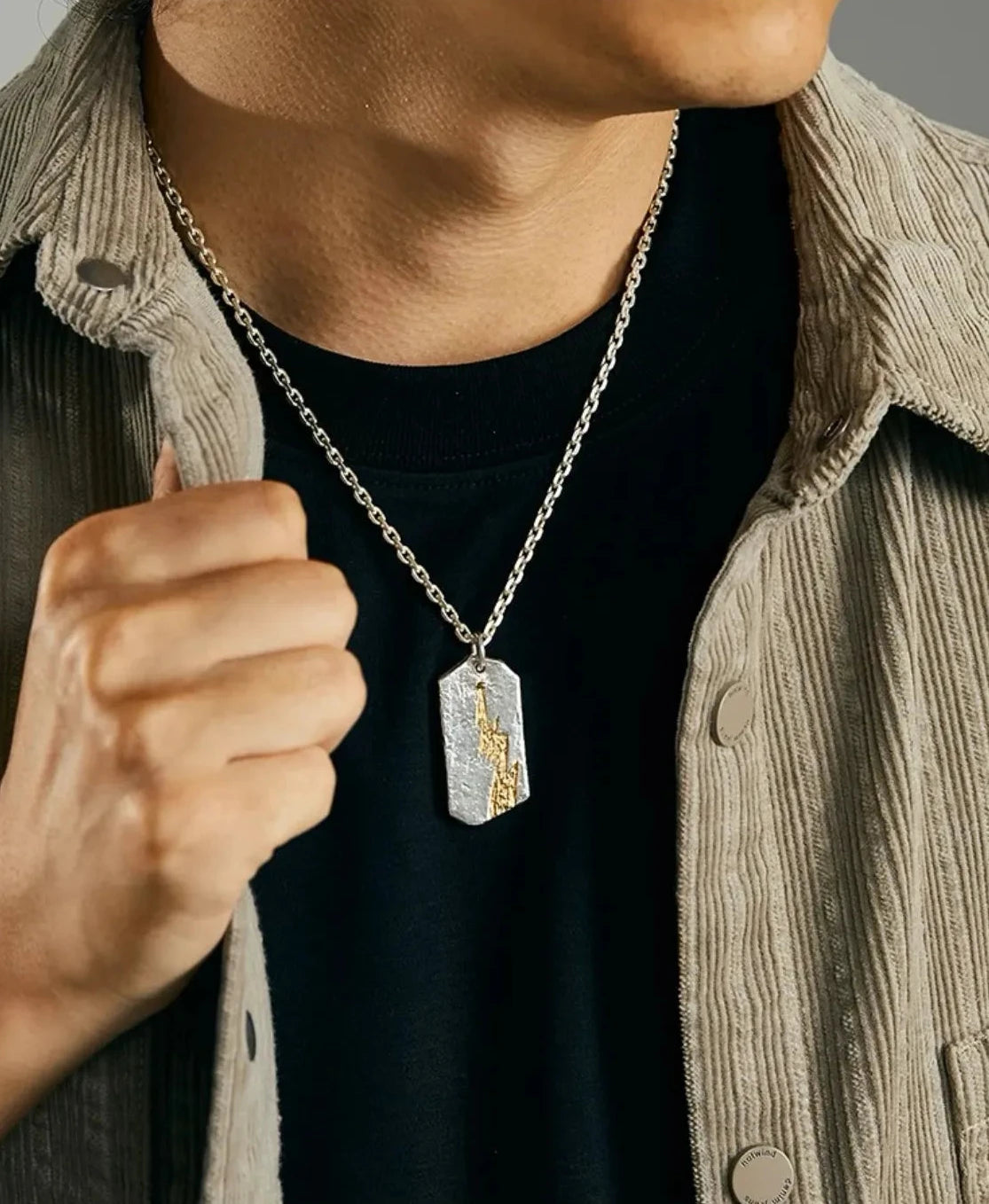 Man wearing the Thunderbolt silver necklace styled with a corduroy jacket and black t-shirt