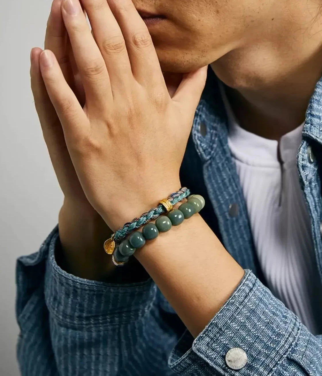 Lifestyle shot of a man wearing a Sashiko indigo jacket, accessorized with the green Prajna bracelet for an artisan aesthetic
