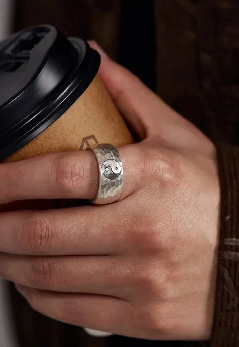 Lifestyle shot of a man wearing the Yin Yang ring on his index finger, holding a coffee cup, dressed in a vintage brown corduroy shirt