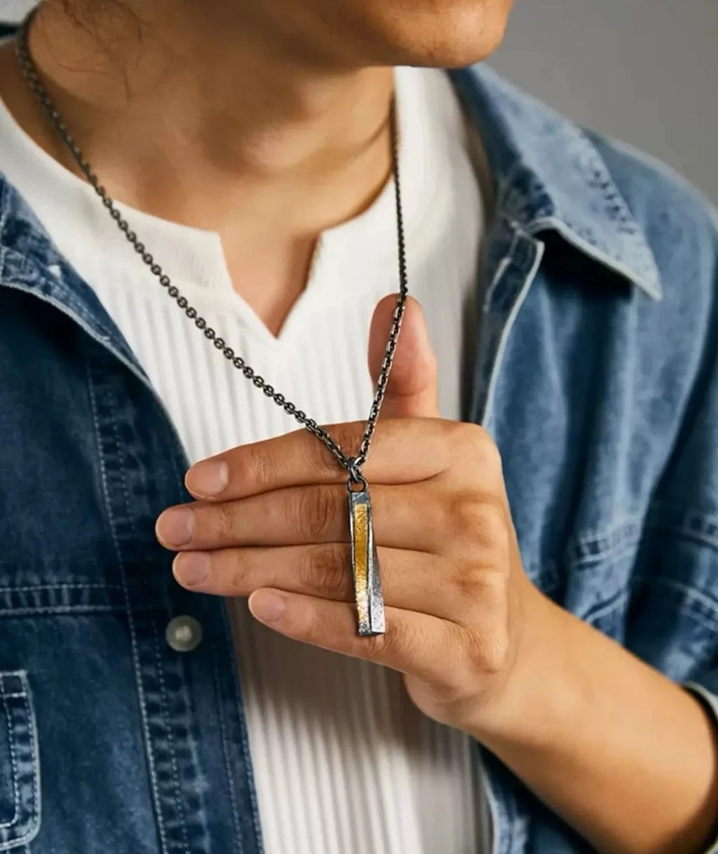 Model holding the twisted bar pendant, demonstrating the tactile texture and size relative to the hand