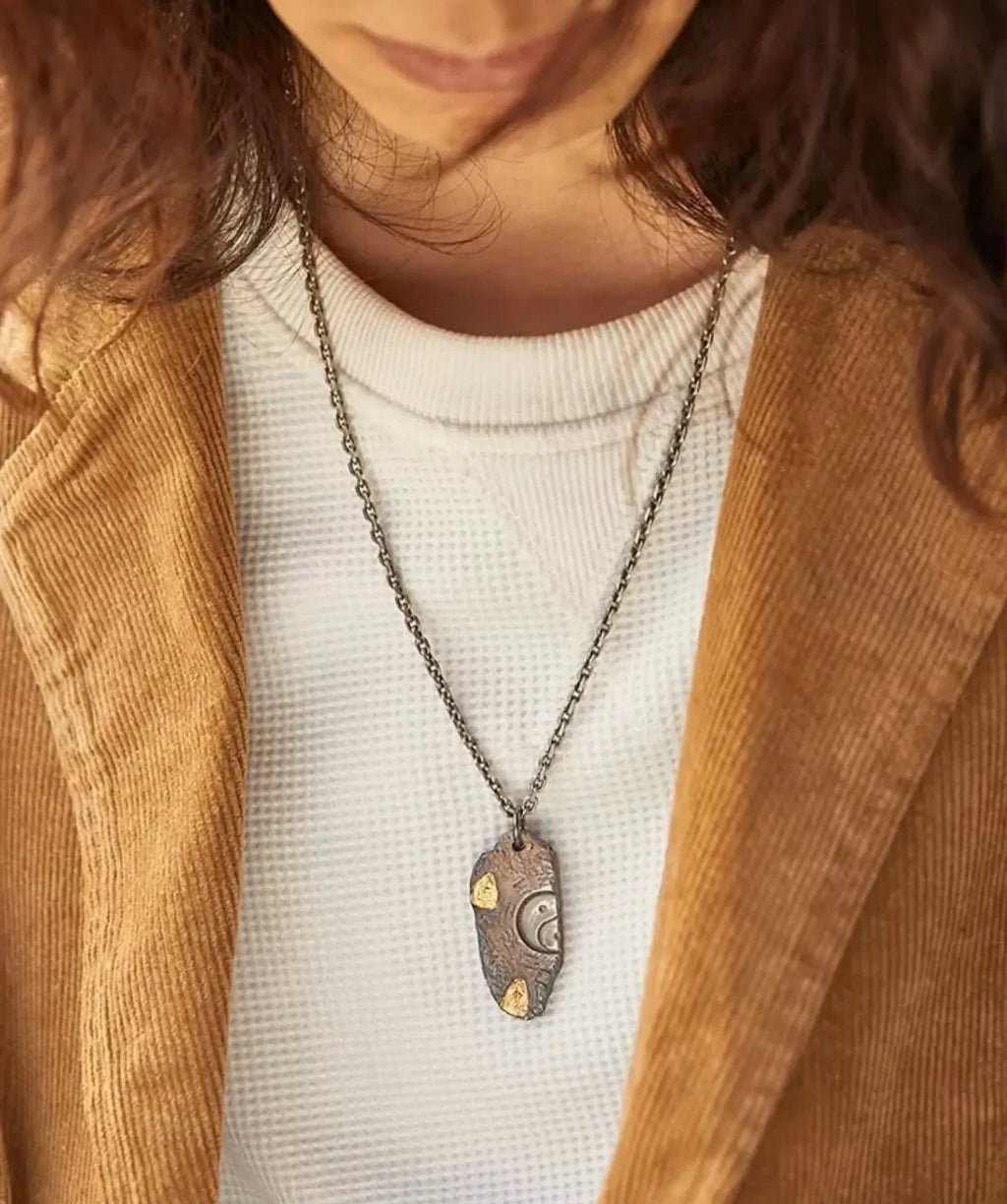 Lifestyle shot of a model wearing the Bagua necklace, highlighting the unique silver and bronze color palette