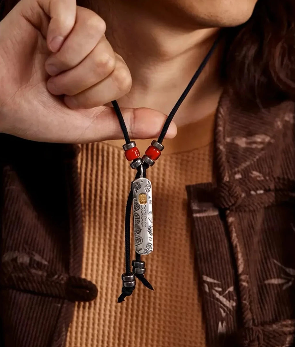 Close-up of a model holding the guardian charm, highlighting the contrast between the silver tag and red cinnabar beads