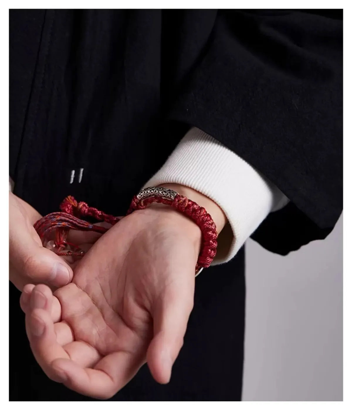 Lifestyle shot of a man wearing the red fortune bracelet, creating a striking contrast against his black jacket.