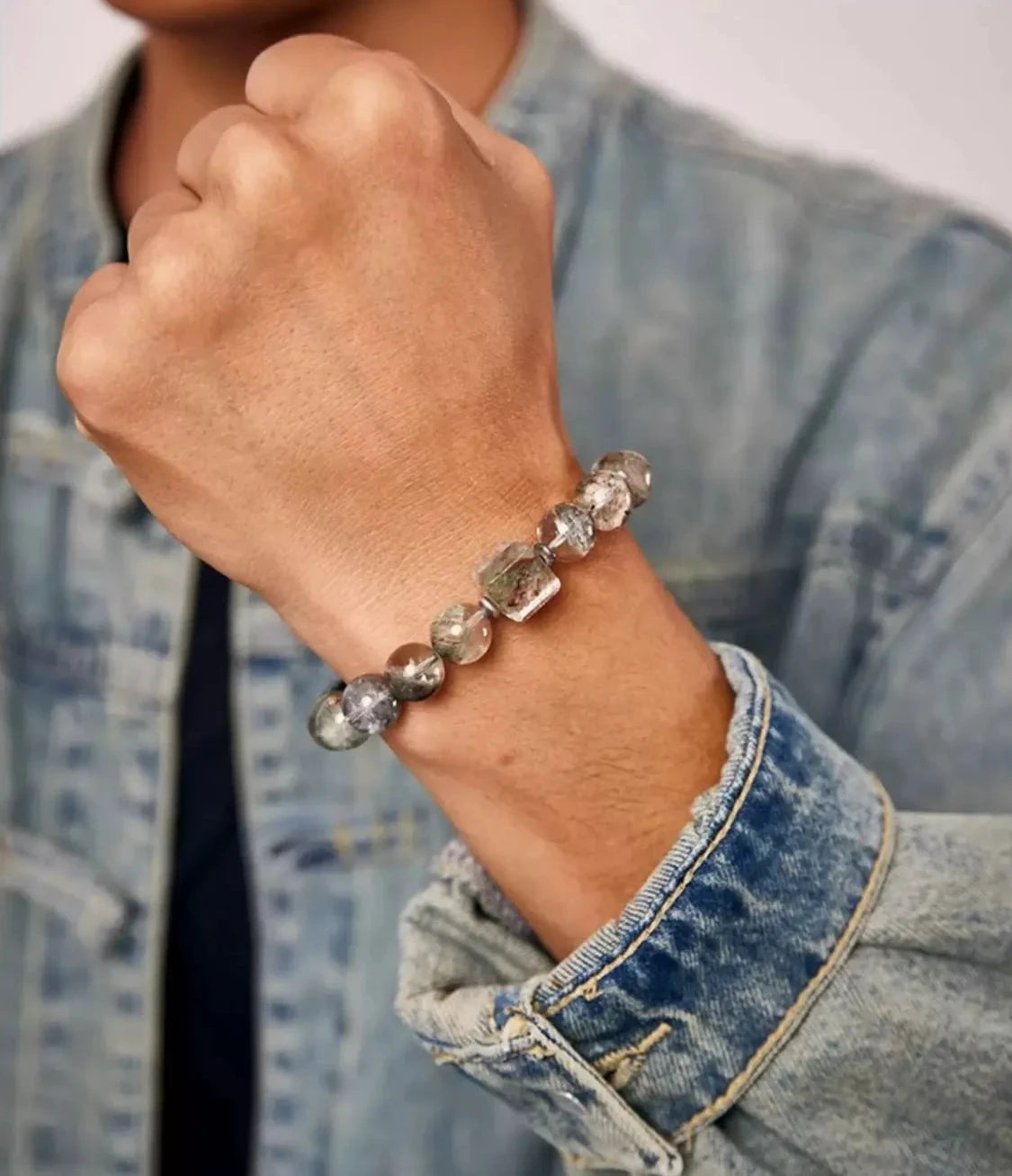 Lifestyle shot of a man adjusting the bracelet, showing how the earthy tones match a vintage acid-wash denim jacket