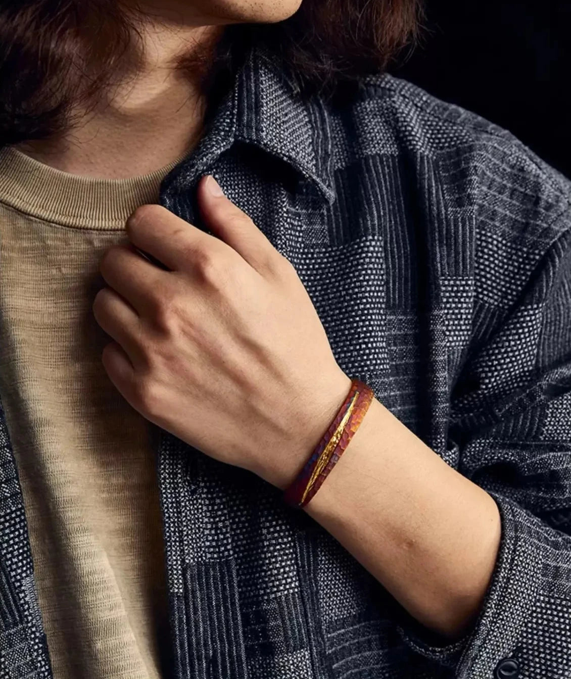 Perspective shot of the bronze-colored bangle, focusing on the light reflecting off the uneven hammered surface and the central gold detail