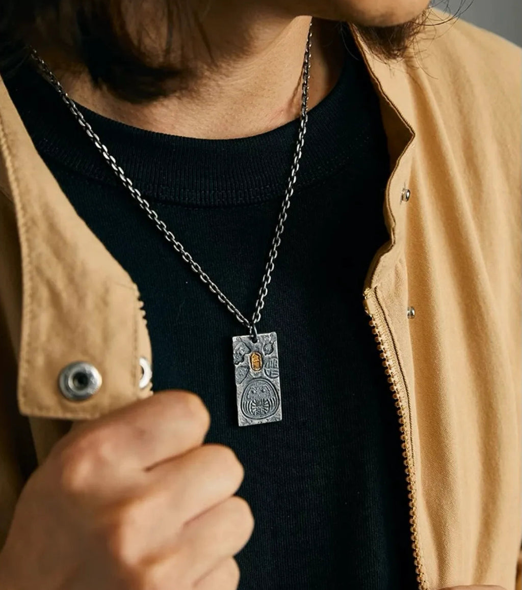 Man wearing the silver Fortune Key necklace styled with a beige jacket, showcasing the pendant's size and look