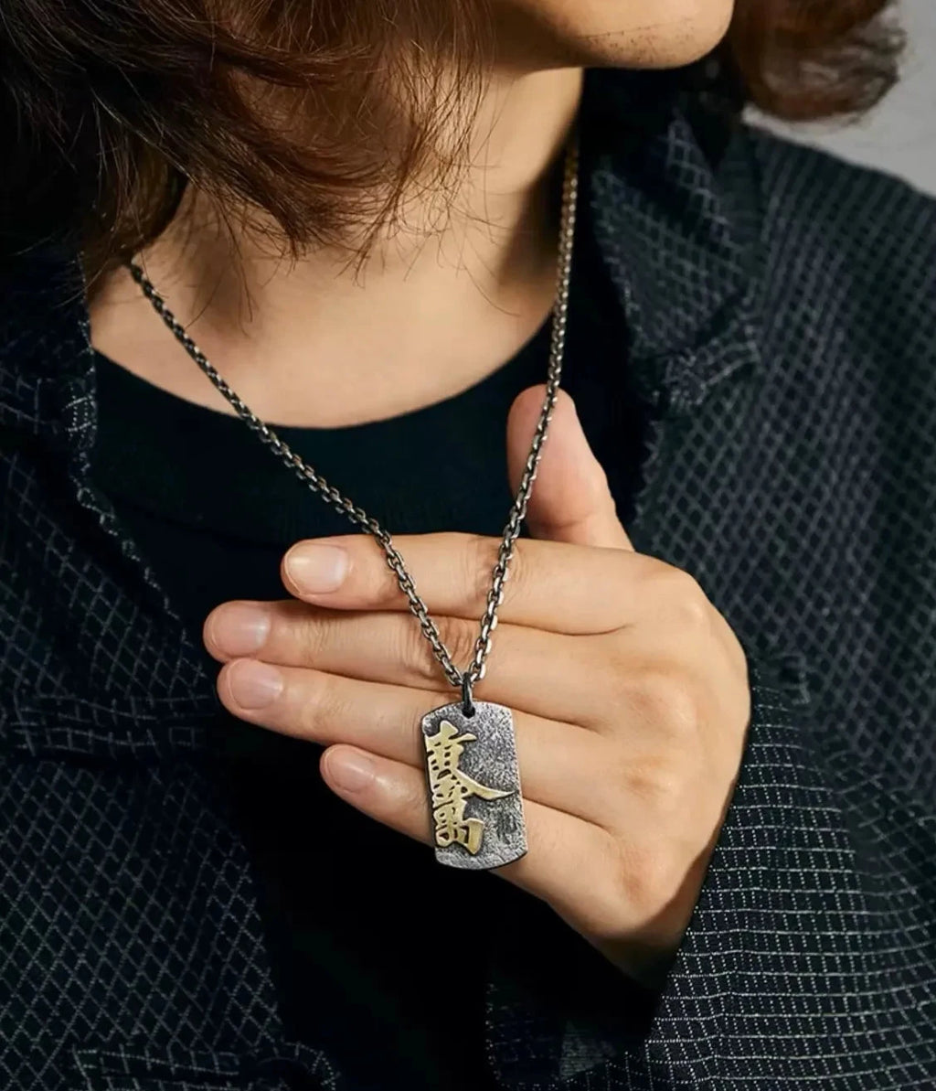 Close-up of a model holding the Fortune necklace pendant, highlighting the gold and silver contrast