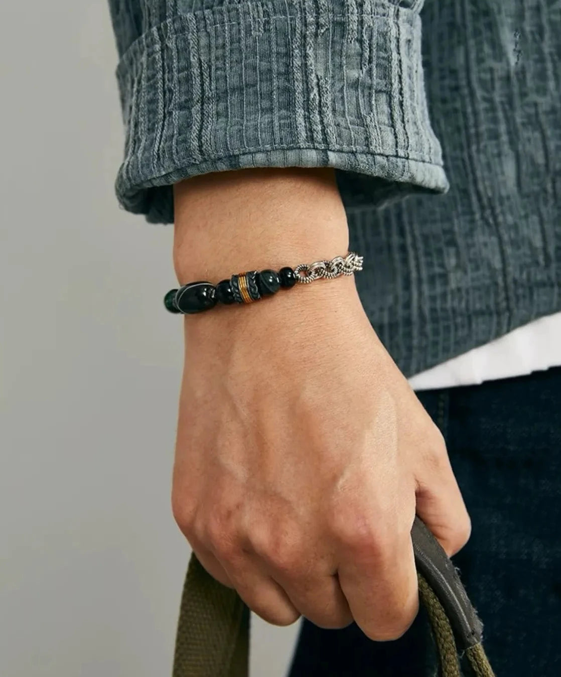 Lifestyle shot of a man wearing the Chasing bracelet, showcasing the bold contrast between the silver chain and the dark gemstones