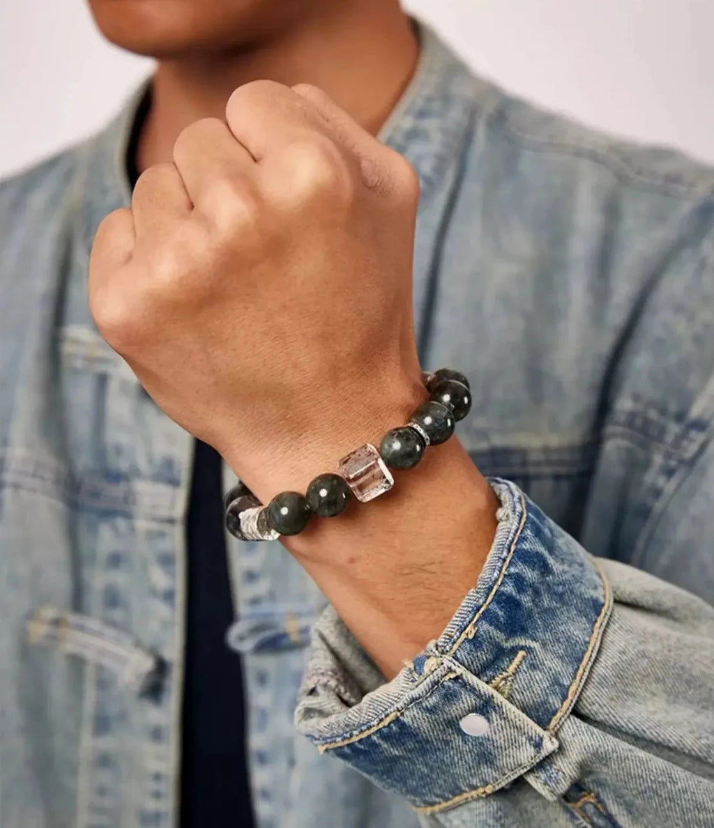 Lifestyle shot of a man adjusting the green and red quartz bracelet, styled with a vintage washed denim jacket