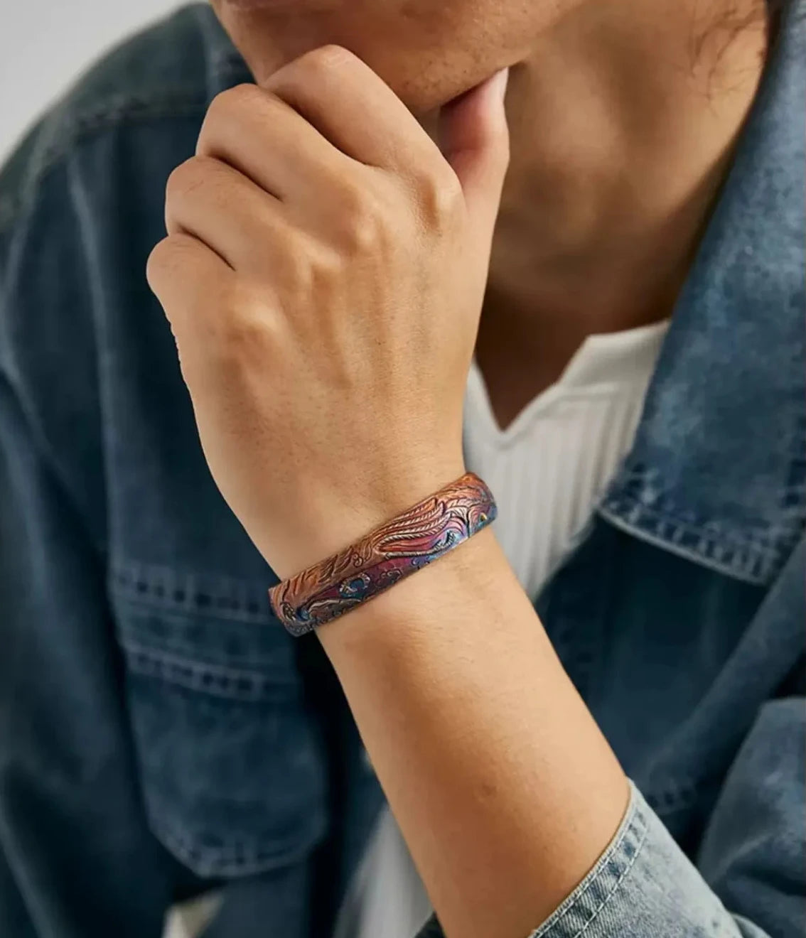 Lifestyle shot of a model wearing the phoenix bangle with a denim jacket, showing how the blue patina matches denim fabric