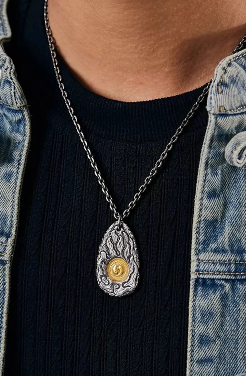 Front view of a model wearing the oxidized silver flame necklace with a gold center, styled with a denim jacket