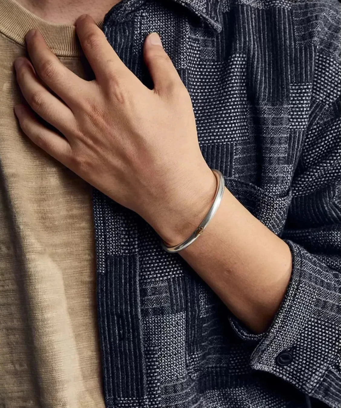 Lifestyle image of a man wearing the Wukong Cloud bangle, the matte silver finish blending perfectly with earth-toned casual wear