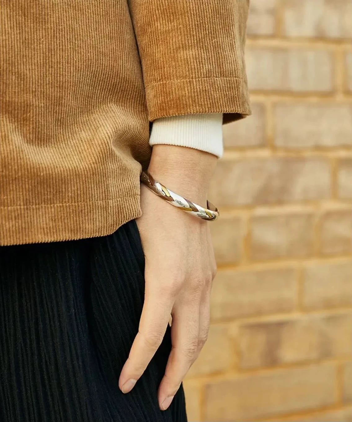 Close-up detail of the bangle on the wrist, showing how the twisted light reflection enhances the texture of the outfit
